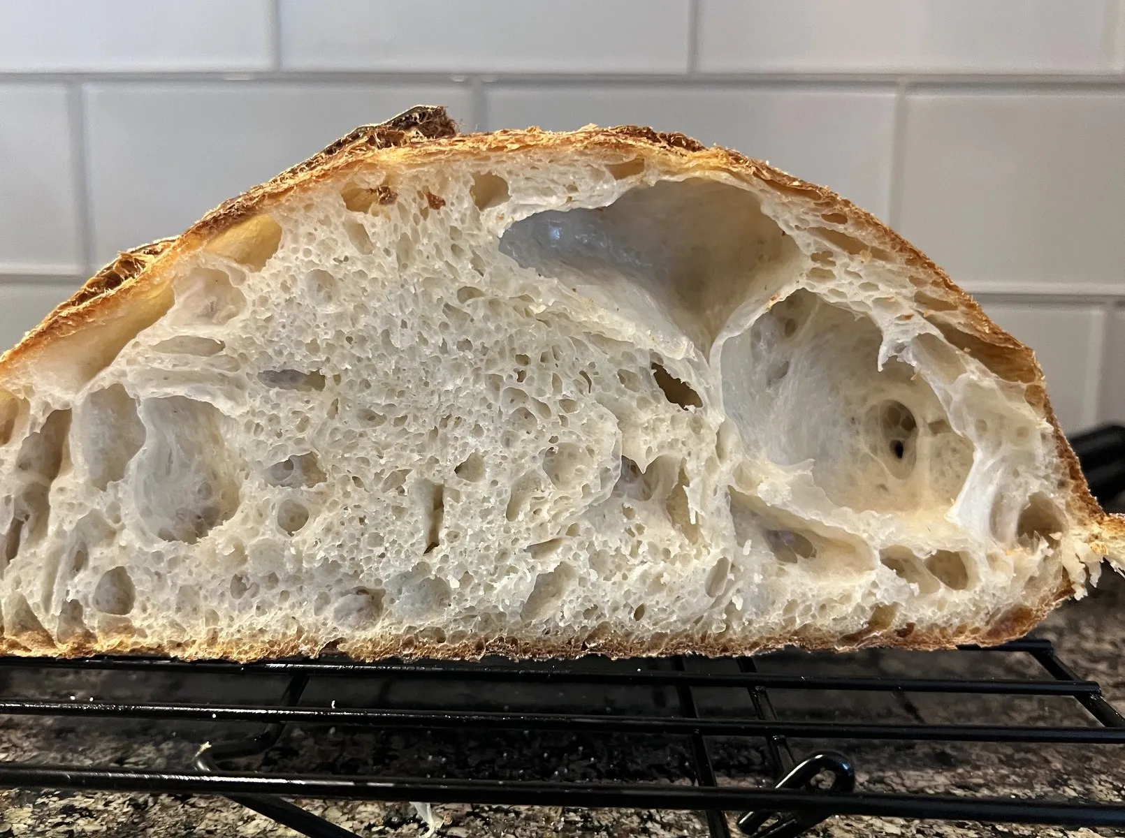 A cut loaf with a large hollow under the top crust and a tighter crumb below it.