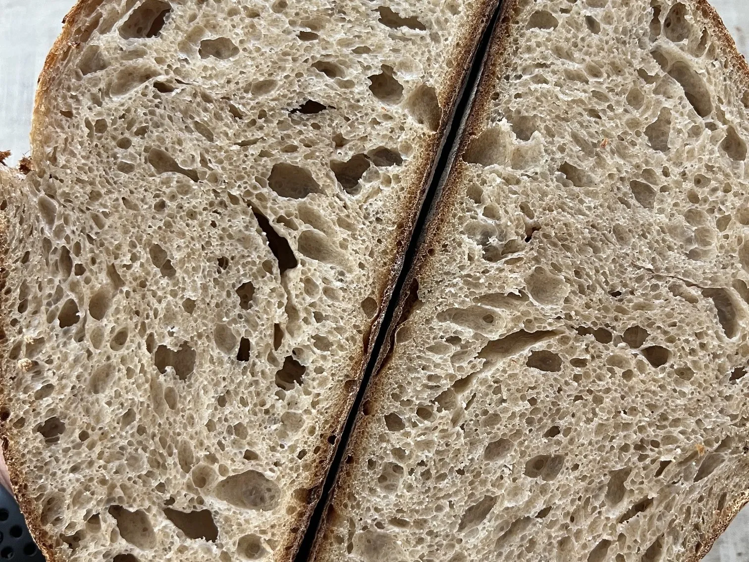 The two halves of a cut loaf, showing an open, even crumb with small and medium holes spread throughout.