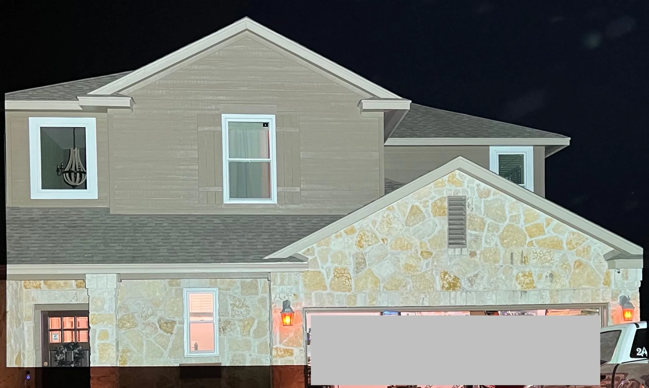 The front of the house at night lit by a full-white projection, with a gray box covering part of the image.