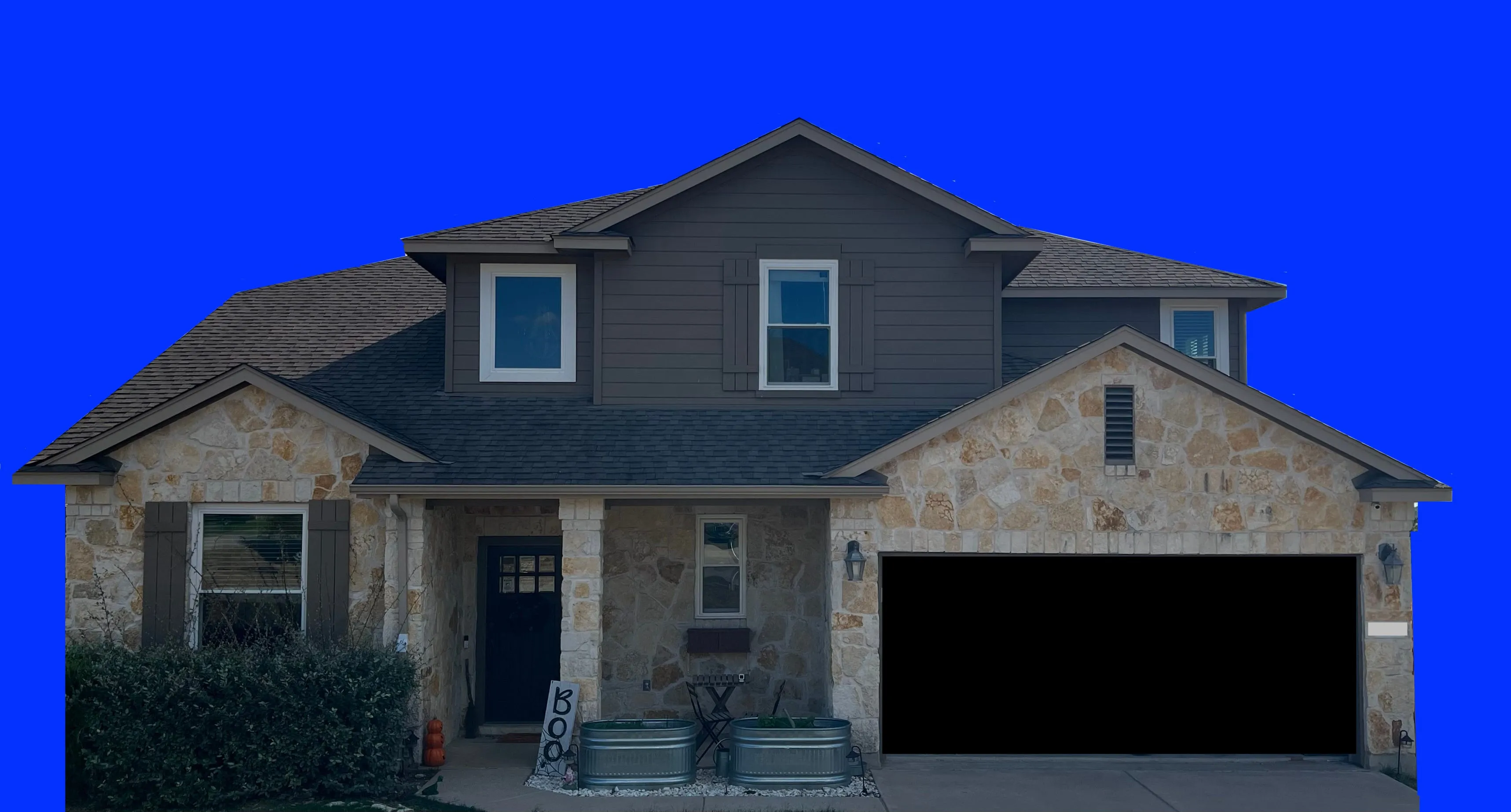 A daylight photo of a two-story stone and siding house with the sky masked out in solid blue and the garage door masked in black.